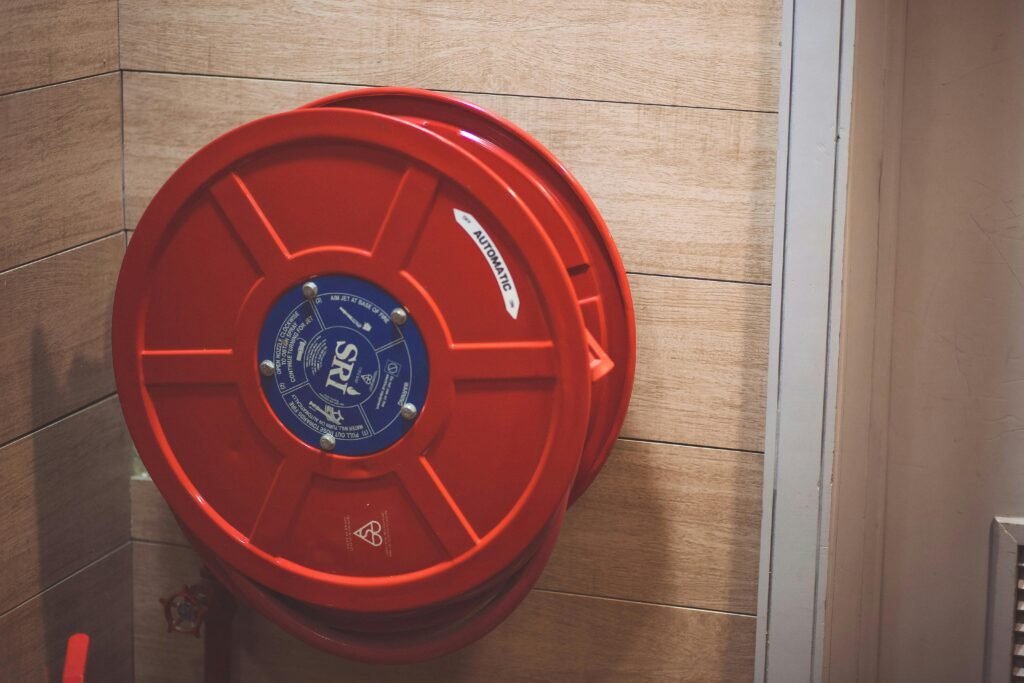 A red fire hose reel mounted on a wooden wall indoors for safety.