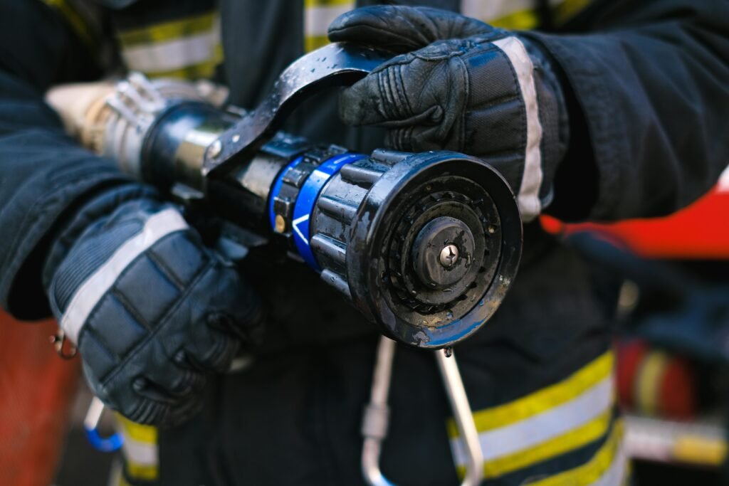 Detailed close-up of a firefighter in gear holding a water hose nozzle, emphasizing safety and emergency readiness.